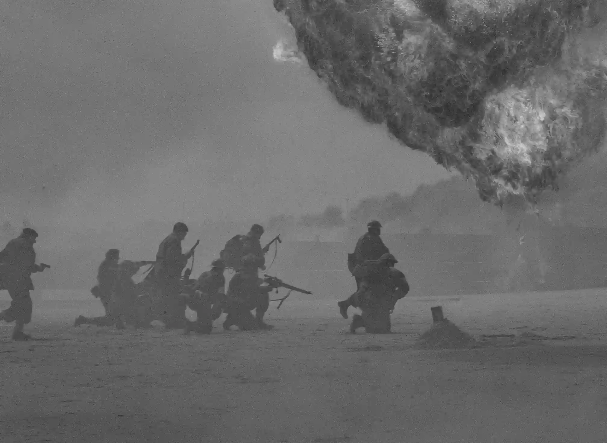 一張黑白照片,畫面右側發生巨大爆炸,一群士兵正在煙霧瀰漫的地方往前進。
