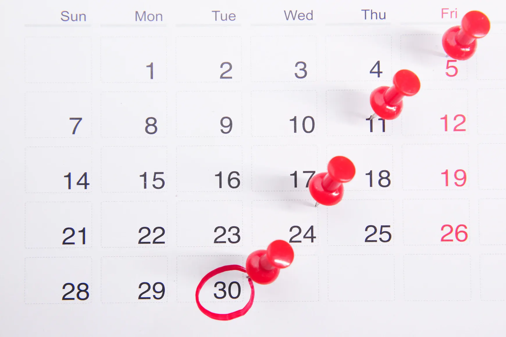 一張日曆，上面用紅色圖釘標示出幾個日期，其中「30」被紅筆圈起。